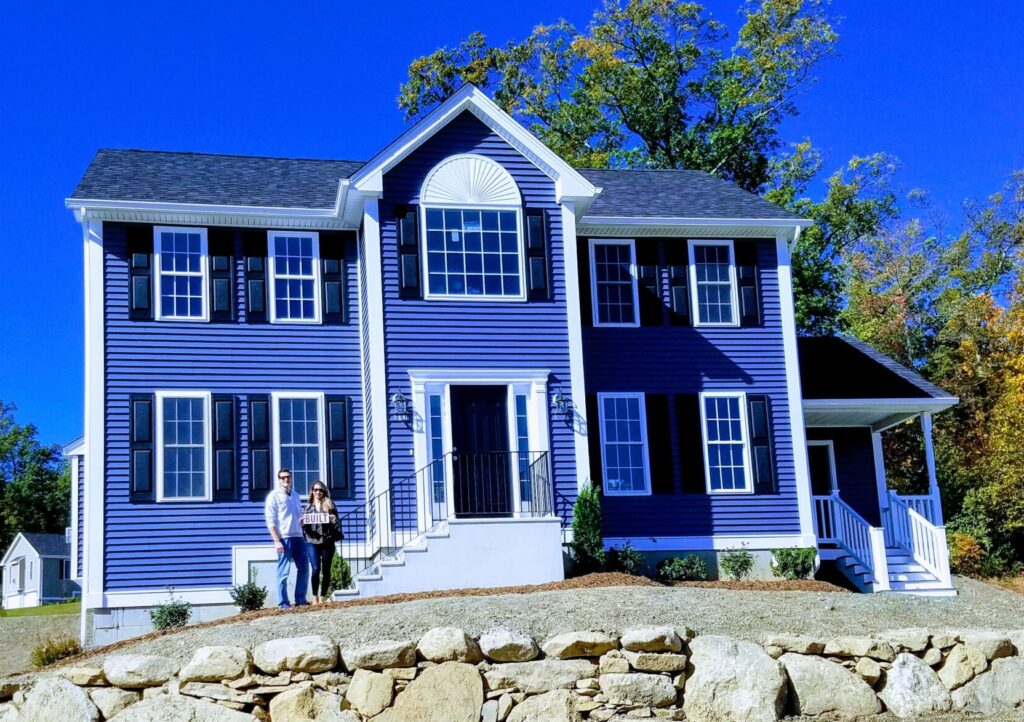 couple smiling in front of newly purchased blue home