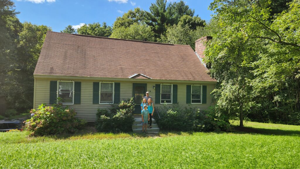 family smiling on the front steps of their new home