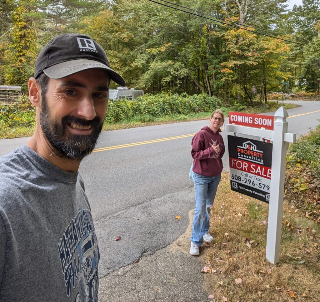 Phil and Heidi standing by For Sale sign