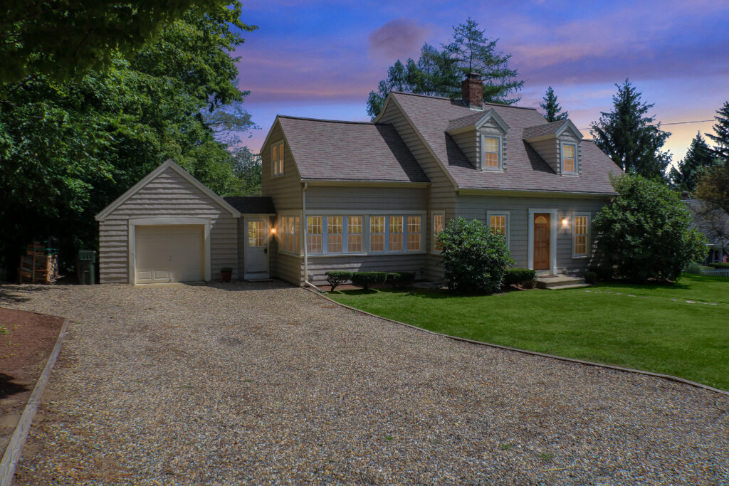 gray home with single attached garage at dusk with exterior lights