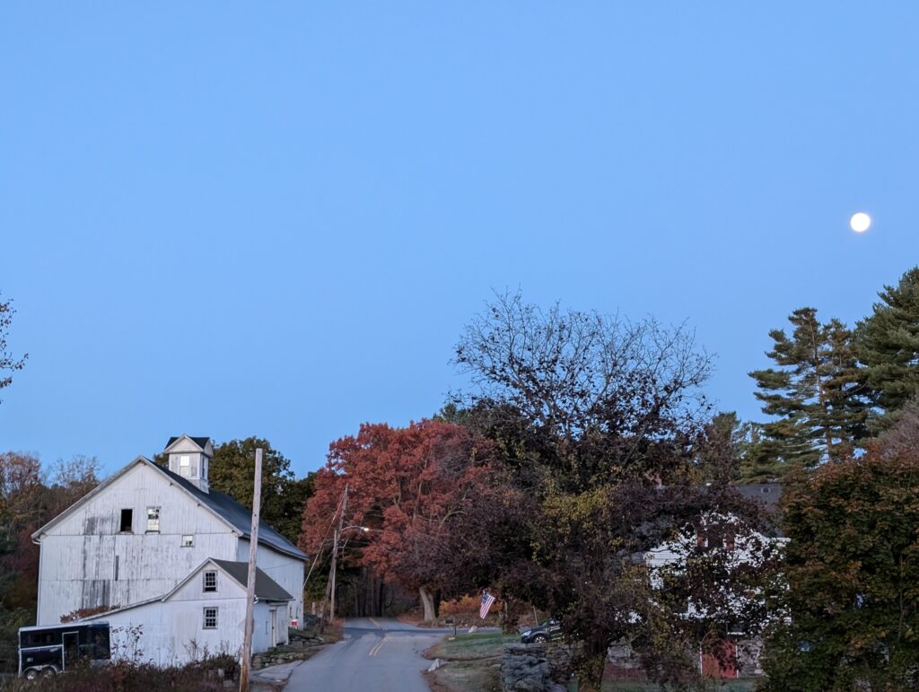 road with old barn during the day - moon in the sky